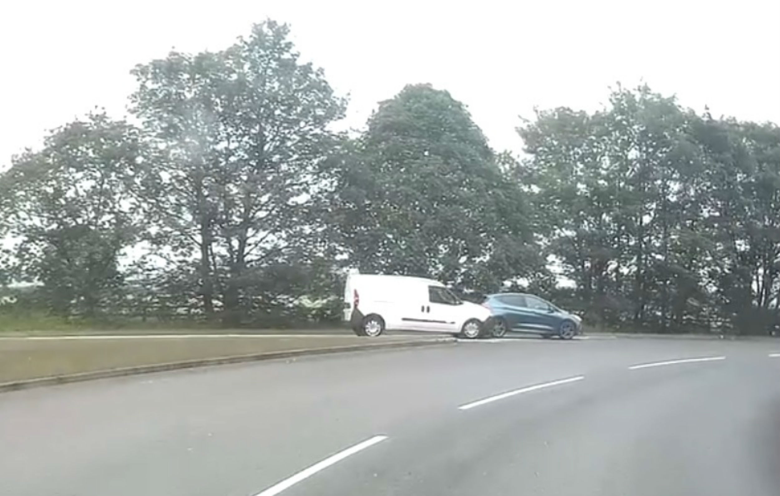 A white van going into the back of another car at a roundabout