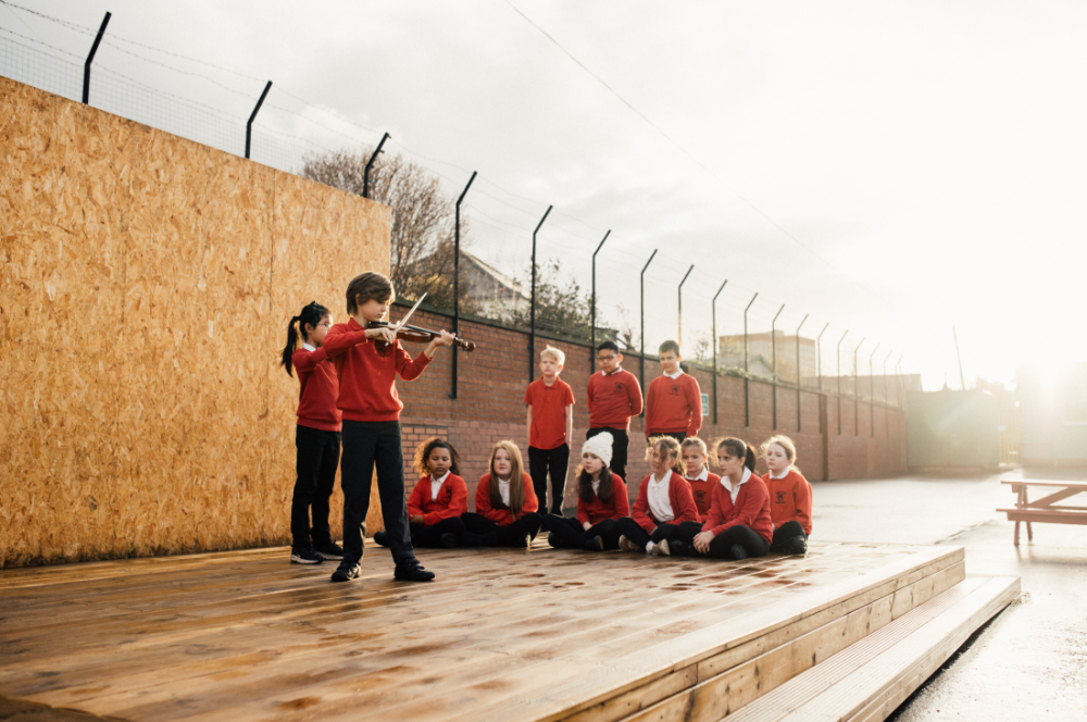 A group of children playing music on an outdoor stage - Entertainment News Scotland