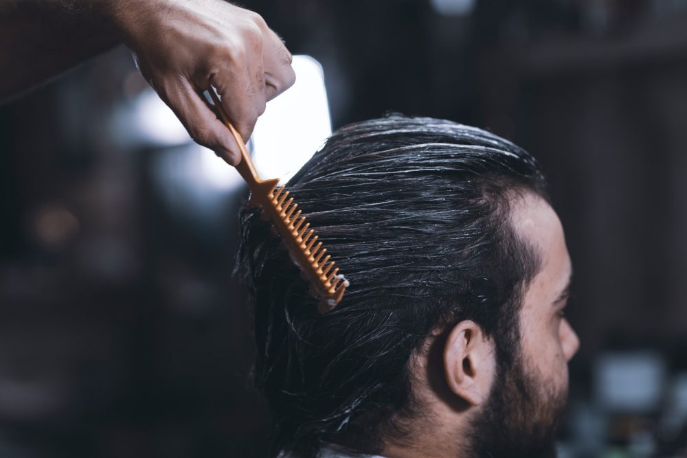 A picture of a man getting his hair combed 