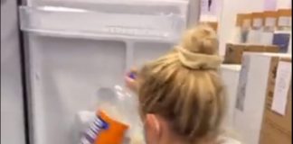 A screenshot from the video of Abby putting the Irn-Bru bottle in the fridge door to check the size of the appliance.