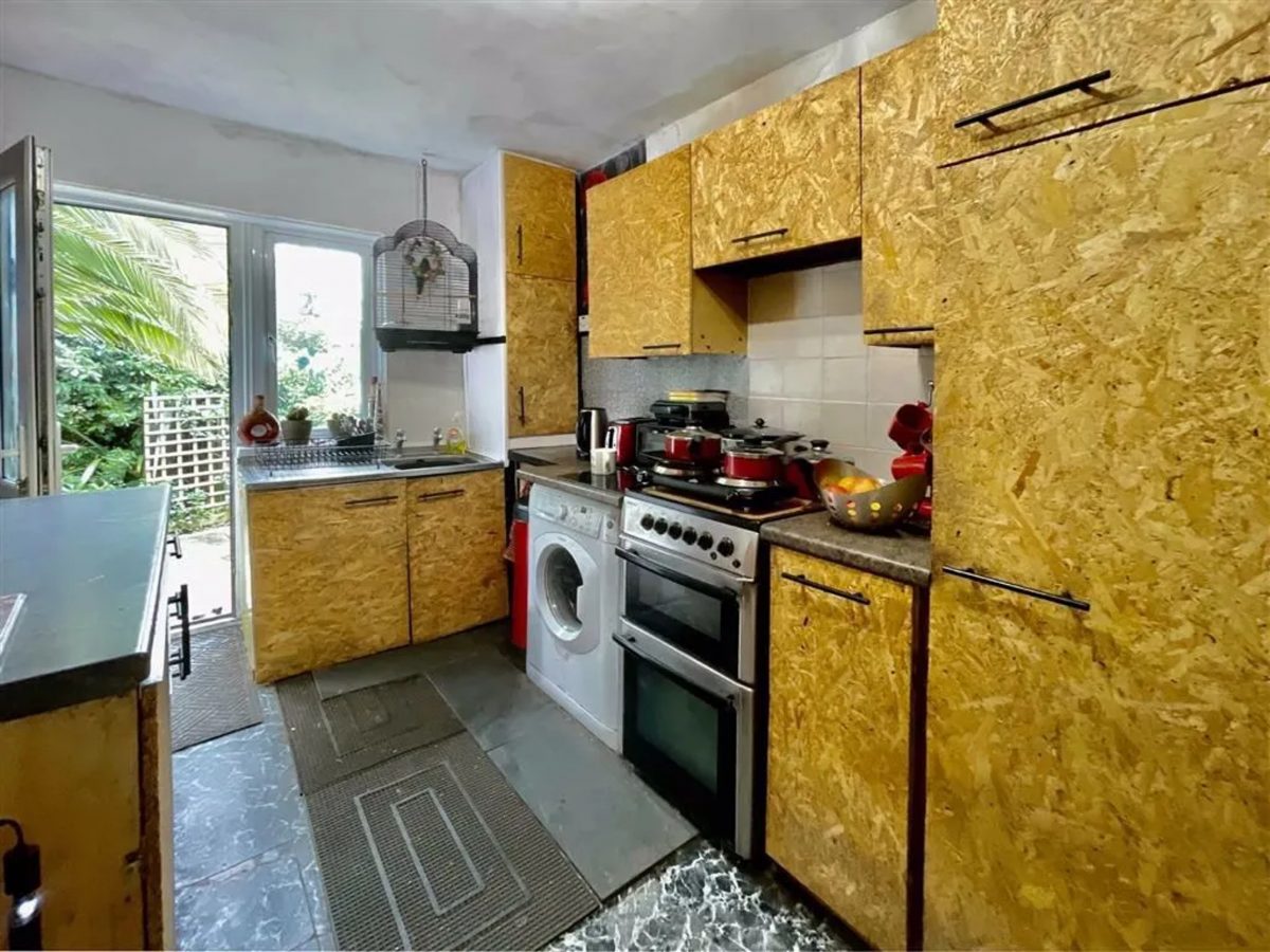 The kitchen in the bungalow, whose cabinets look like they are composed of plywood.