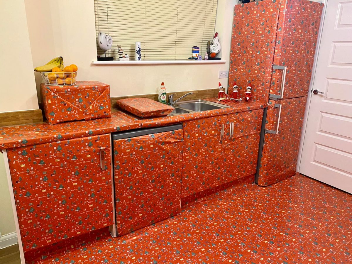 The kitchen wrapped in paper with the Elf on the Shelf dolls on the countertop.