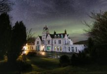Photo of Skeabost House Hotel, with Northern Lights behind it.