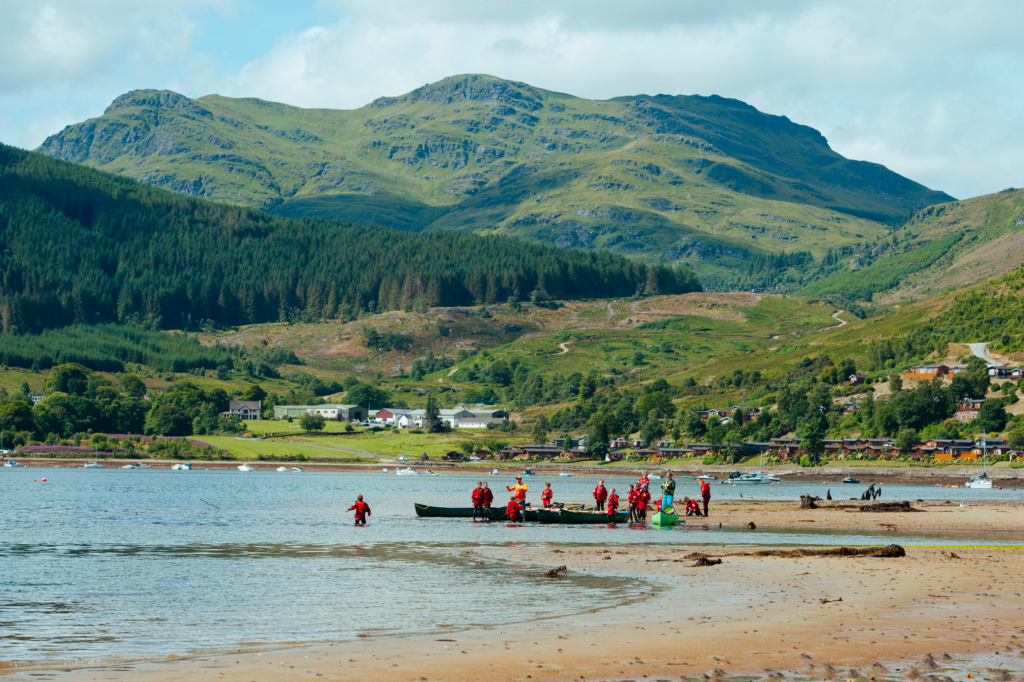 Youngsters on canoes in lake in front of hills and Scottish  landscape.