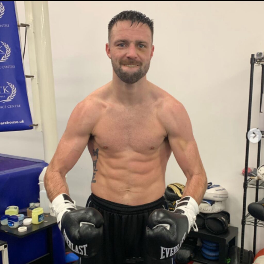 Josh Taylor posing shirtless with boxing gear on.
