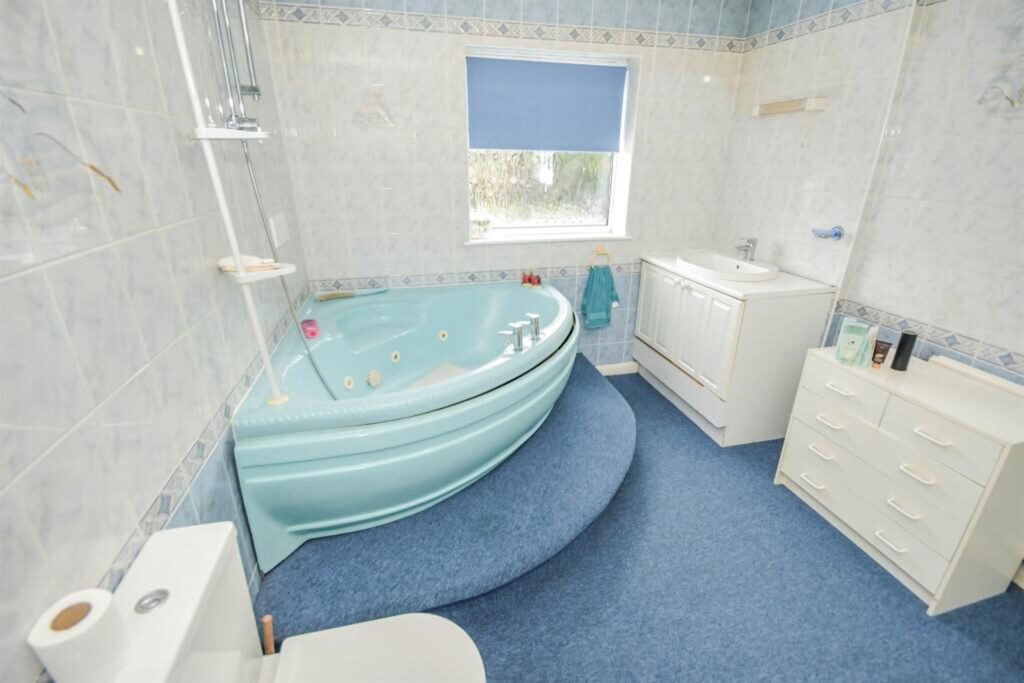 The carpeted bathroom has a jacuzzi bath