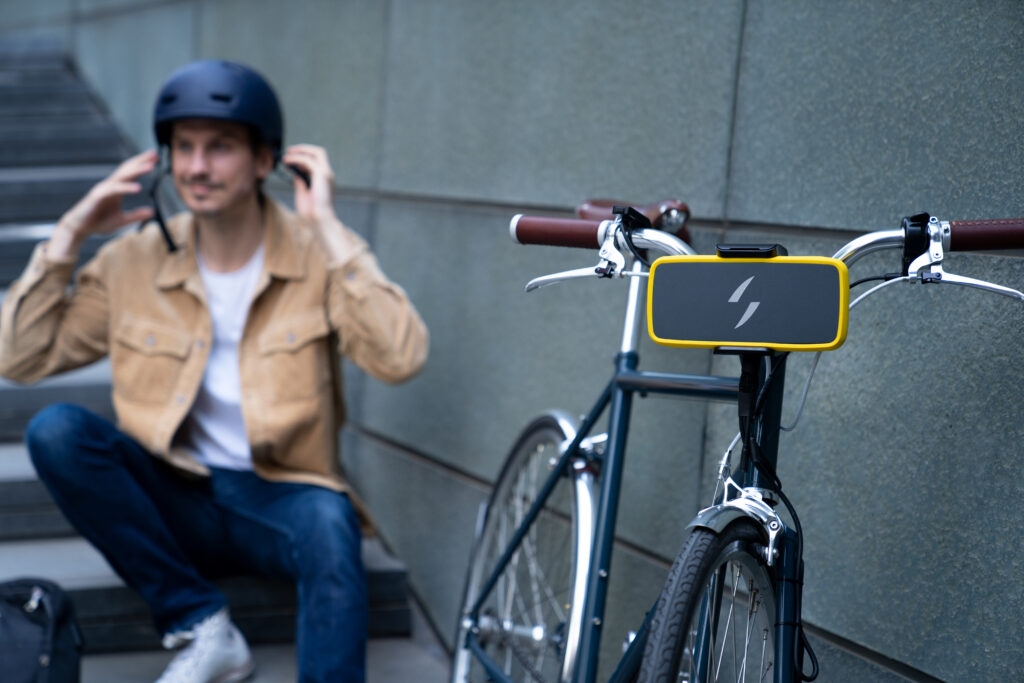 Man sitting next to a bike with the Swytch battery attached to the handlebars.