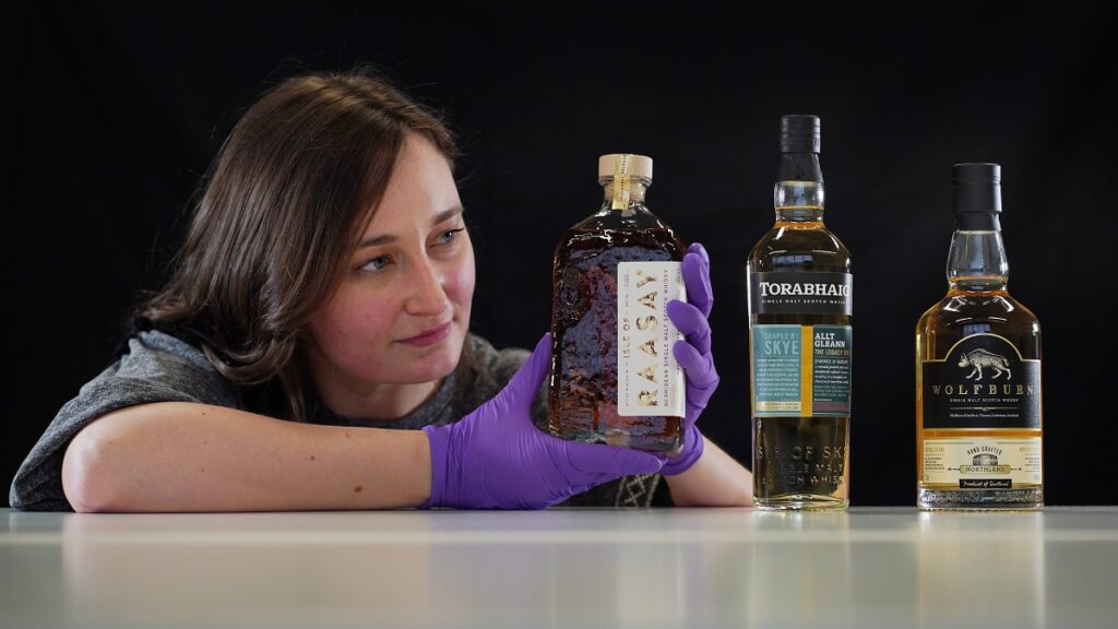 Doctoral Researcher Laura Scobie with bottles of whisky.