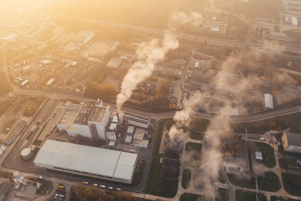 Birds eye view of factory with emissions coming from chimneys.