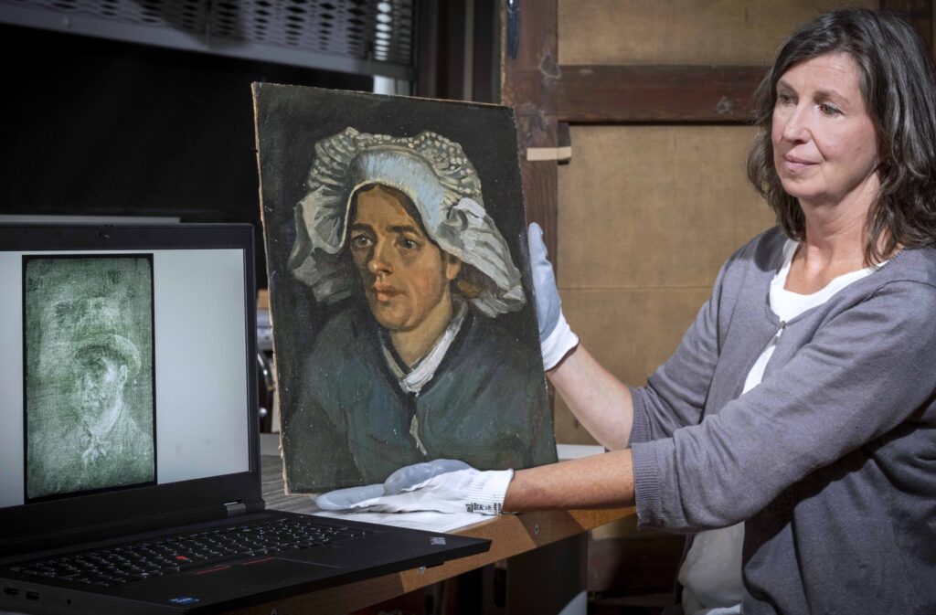 Art conservator with the Head of a Peasant Woman painting, with the x-ray image of Van Gogh's self-portrait displayed on a laptop screen beside her.