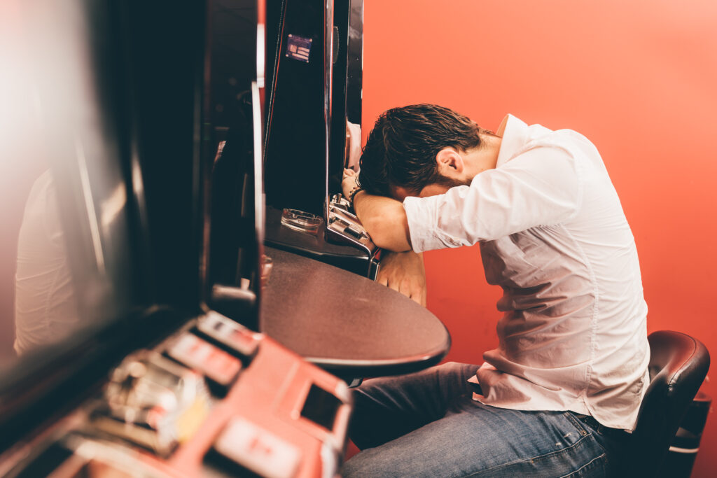 Man slumped at slot machine.
