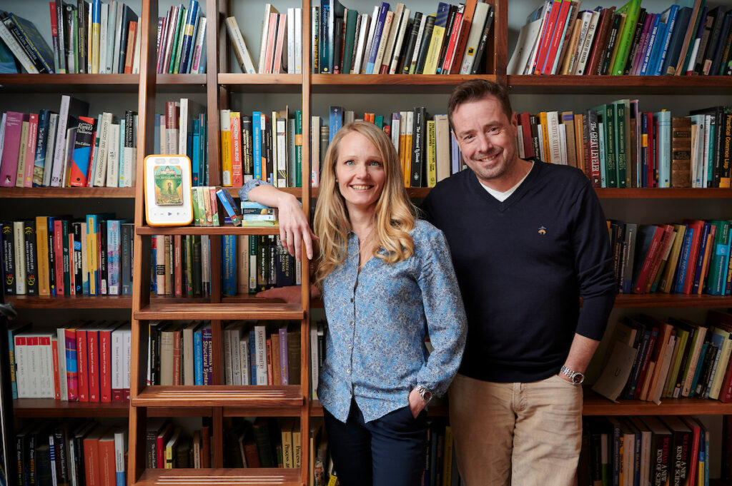 A photo of Voxblock's co-founders Rebecca Lundgren and Tom Williams stood with their product in front of a bookshelf.