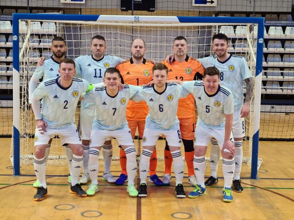 The Scottish National Deaf Futsal Team lineup posing in front of goal.