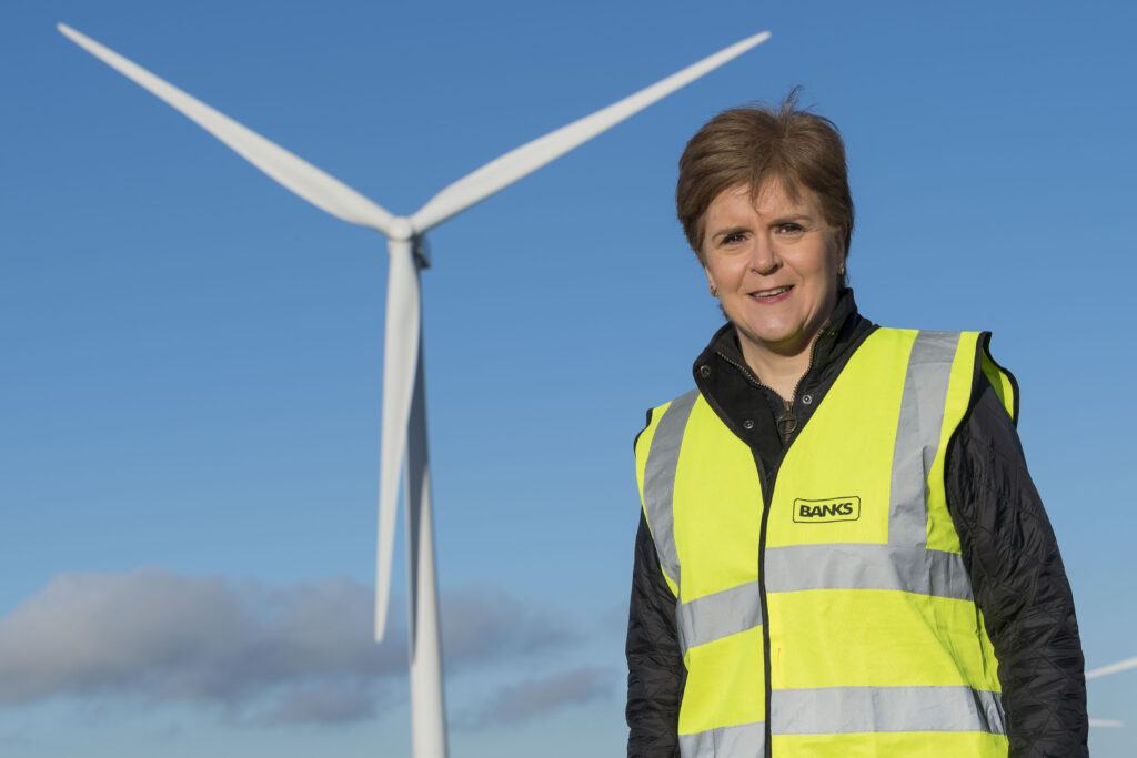 First Minister Nicola Sturgeon standing in front of a wind turbine.