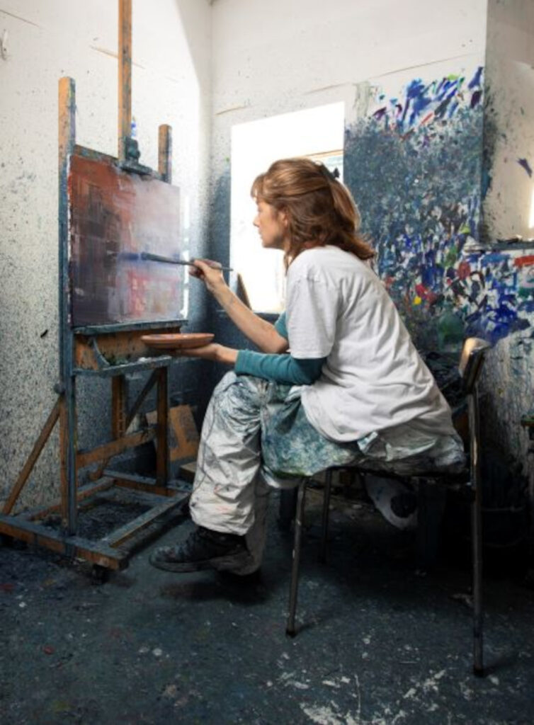 Mairi Clark sitting painting at an adult.