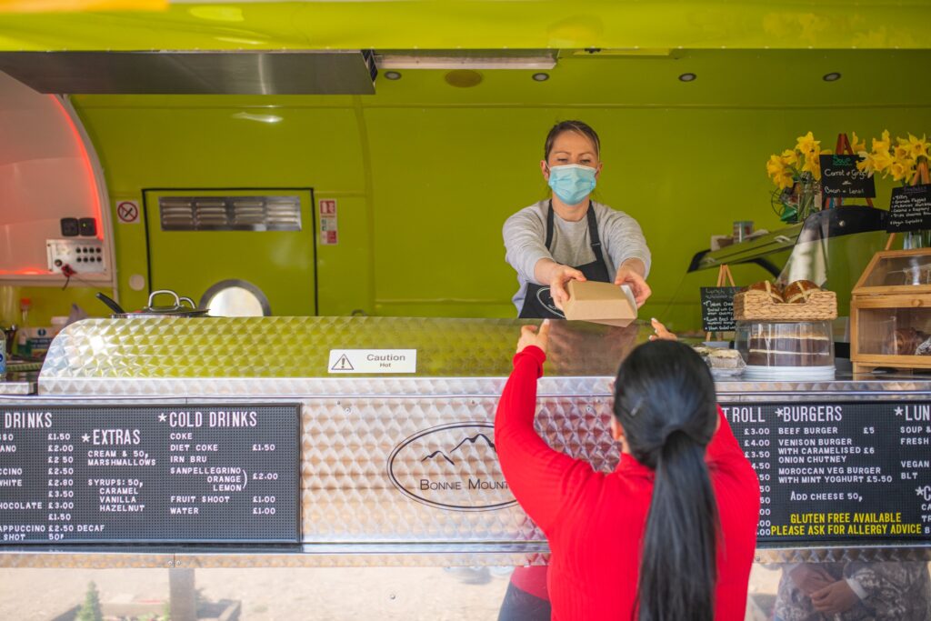 Woman serving a customer from a food truck at the Tea Garden in Comrie Croft.