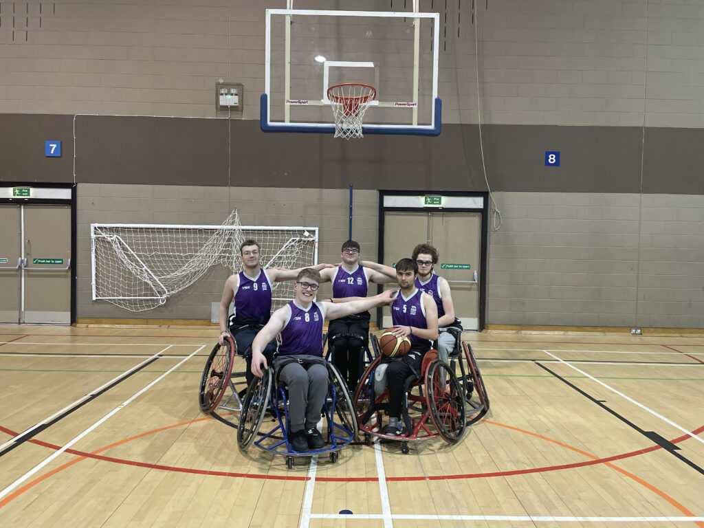 RGU wheelchair team pose below a basket.