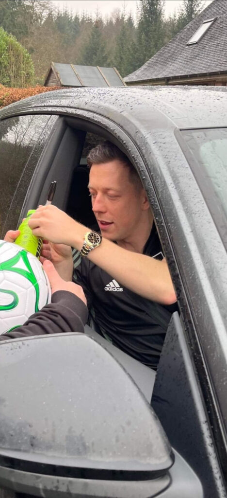 Celtic captain Callum McGregor signing a bottle of Prime