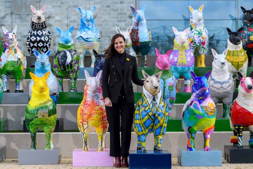 Mairi McAllan MSP stood with some of the decorated sheep sculptures