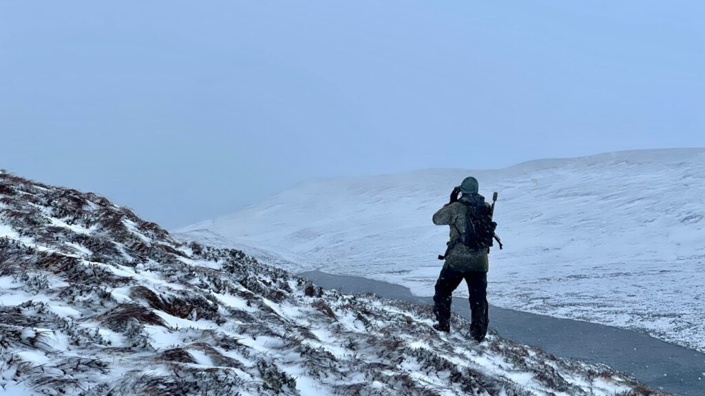 A NatureScot stalker scans the snowy landscape