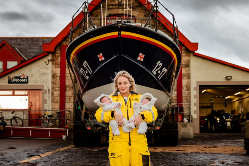 Nicole Fleming in front of a lifeboat with her twin girls