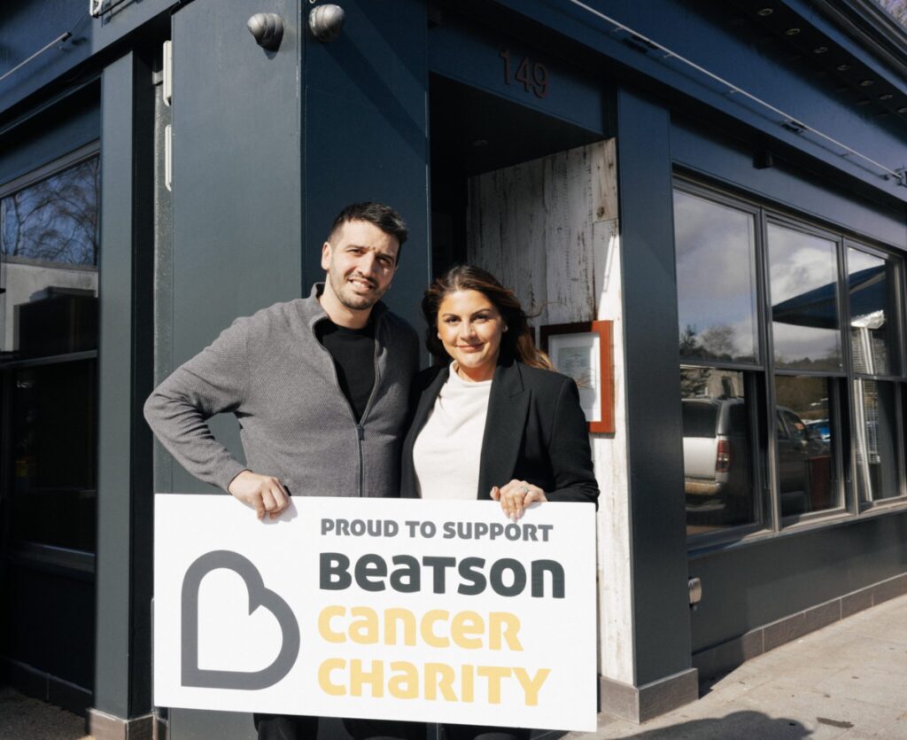 Chef Nico Simeone with his wife Valentina holding a sign for Beatson Cancer Charity.