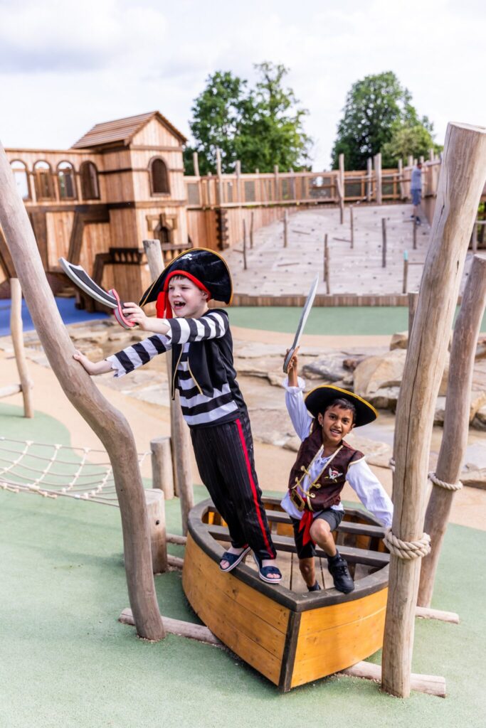 Blenheim Palace Adventure. Two children dressed as pirates playing on a wooden boat