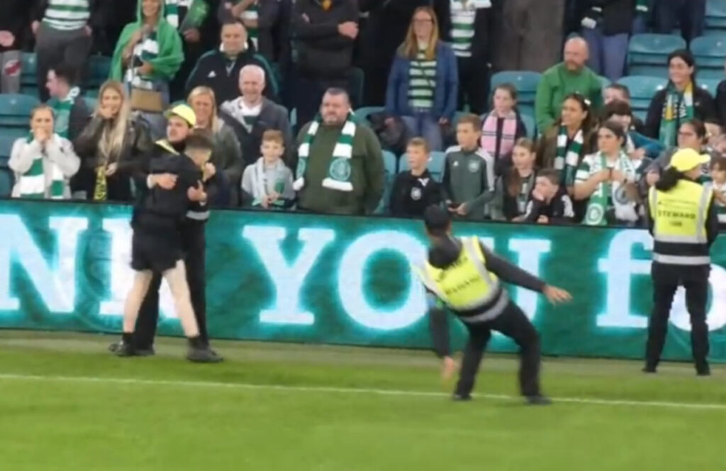 The image shows the steward loses his footing as the pitch invader is apprehended