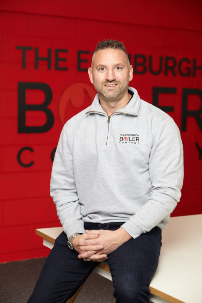 Dougie Bell sitting in front of Edinburgh Boiler Company logo