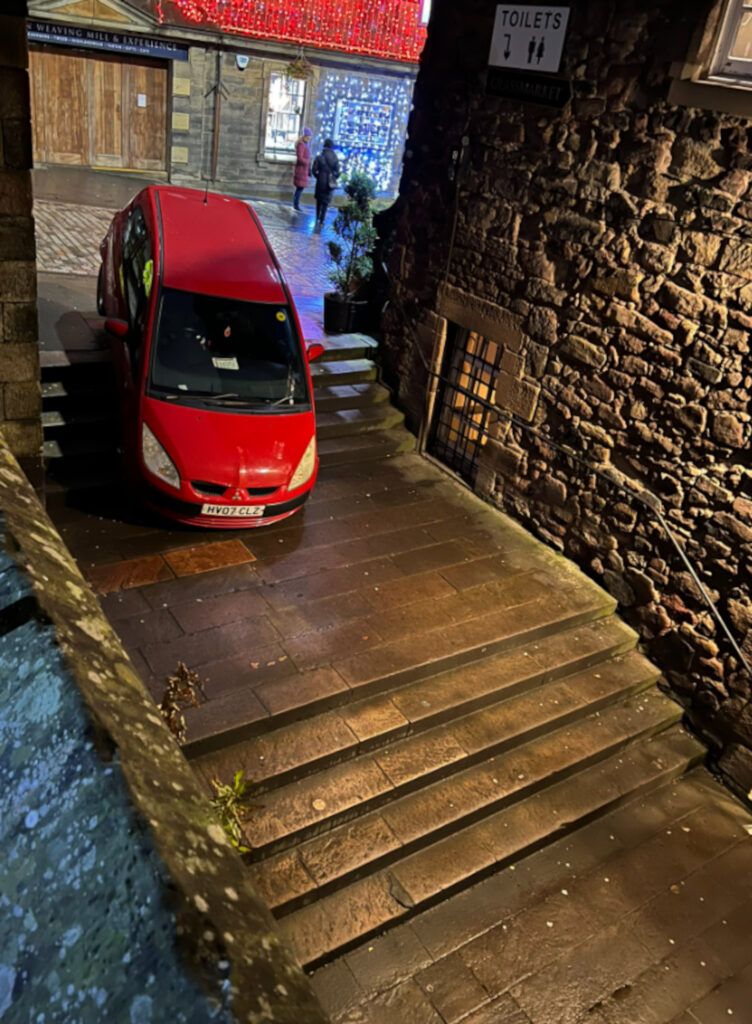 The red car lays abandoned on the steps of Castle Wynd North