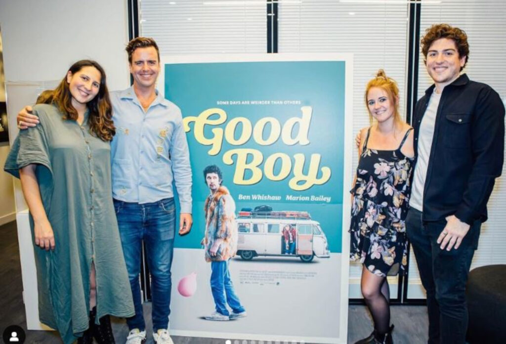 The cast standing at the movie poster.