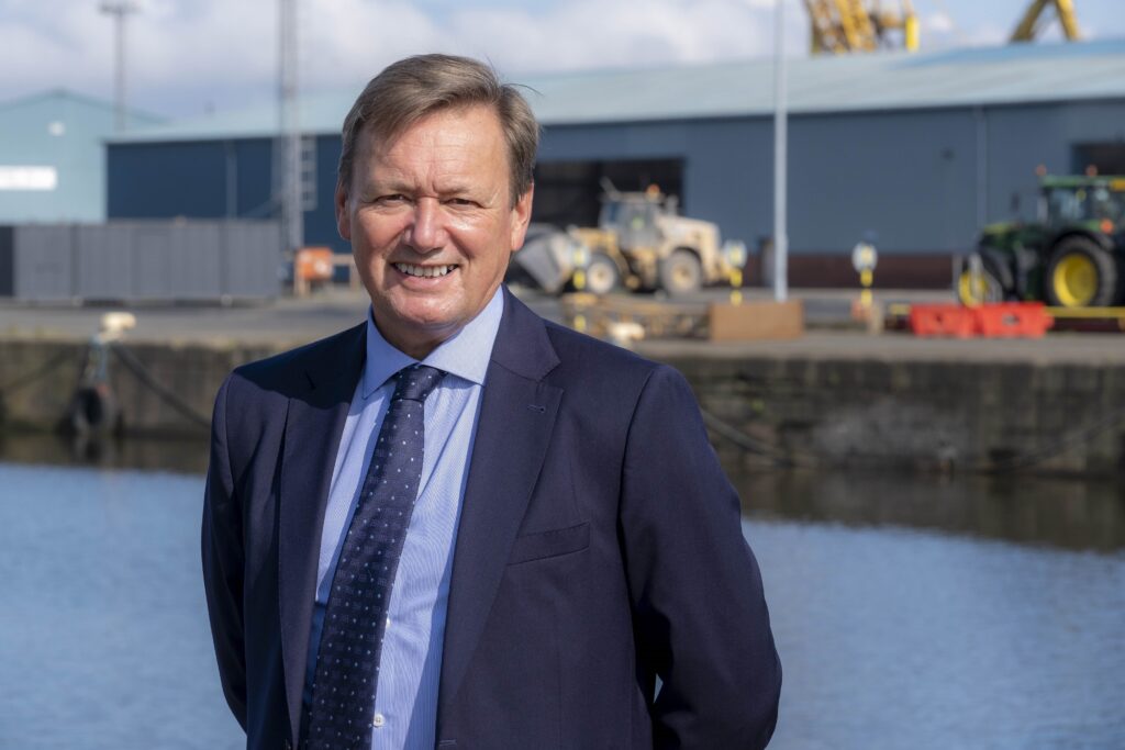 Charles Hammond OBE smiles for photo at a port.