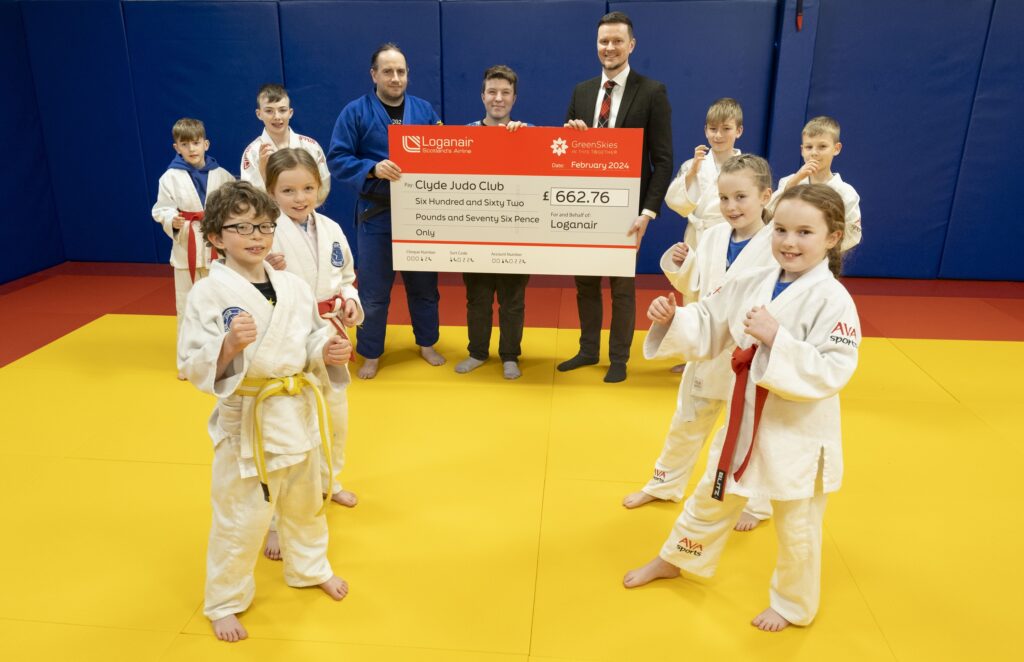 Child students and instructors at Clyde Judo in Paisley pose ready for photo with check from Loganair's GreenSkies fund.
