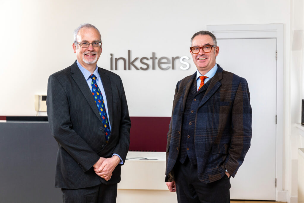 Martin Burns and Brian Inkster smile for a photo in an Inkster office in Glasgow.