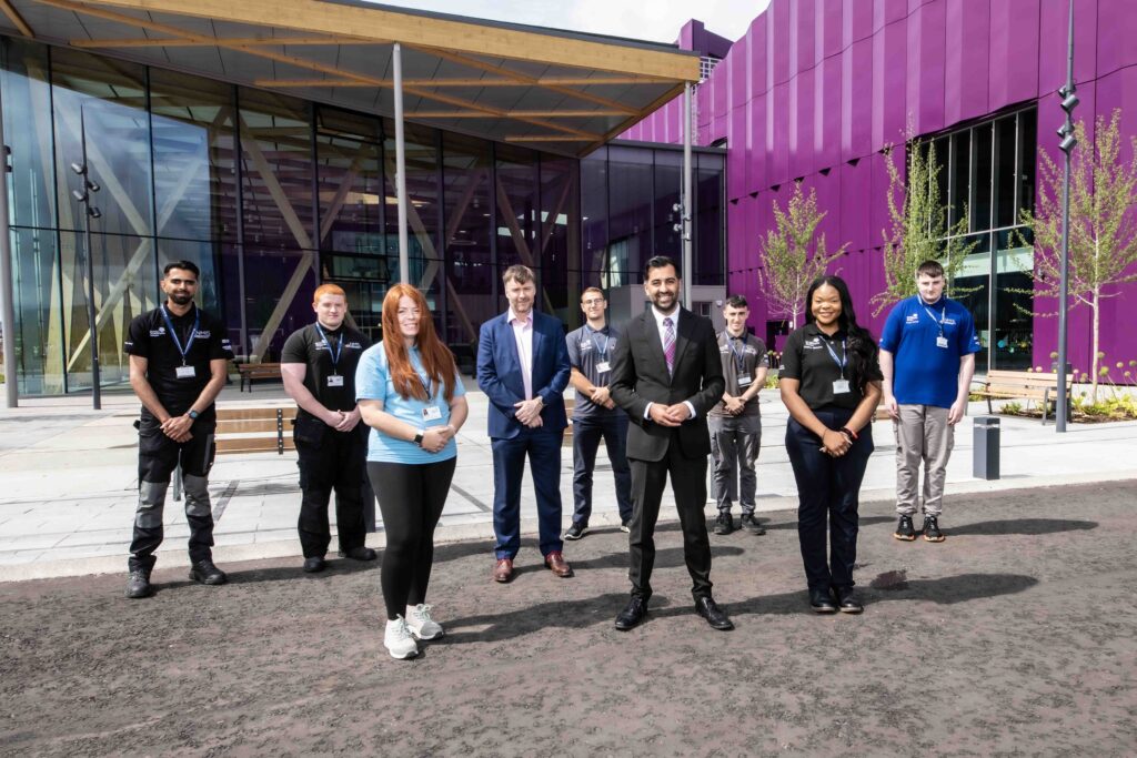 First Minister Humza Yousaf smiles for a photo with NMIS staff and Chief Executive Chris Courtney outside NMIS facility.