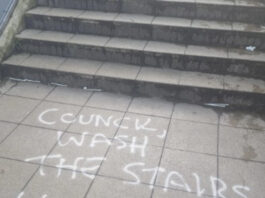 Steps in Brighton with graffiti on the pavement asking for the graffiti to be cleaned up
