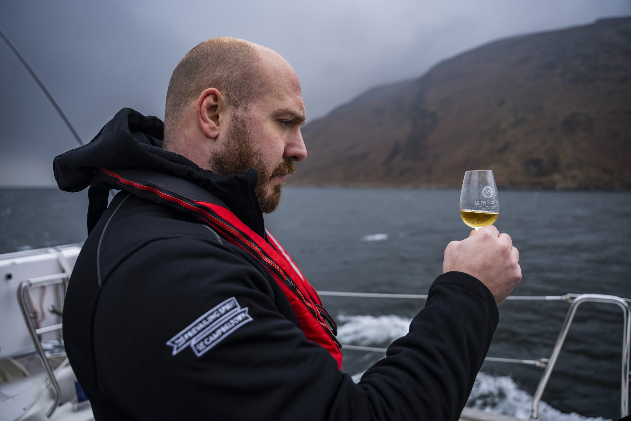 Graeme Johncock inspects a dram of whisky in a glencairn glass whilst on a boat