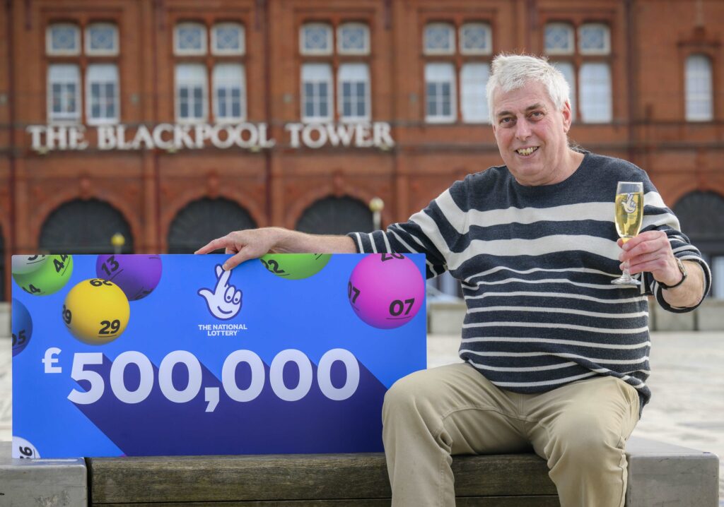 Raymond Young holding £500,000 lottery card outside Blackpool Tower.